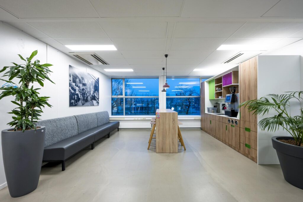 Moderne pantry met zithoek, grote planten en uitzicht op Van der Madeweg in Amsterdam.